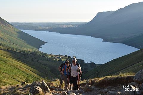 Trekkers walking up a steep hill in the Lake District.