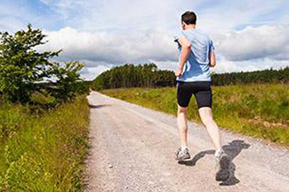 A single runner running on a track in the countryside.