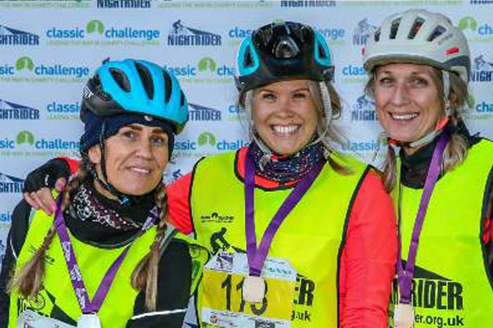 Three cyclists showing off their race event medals.