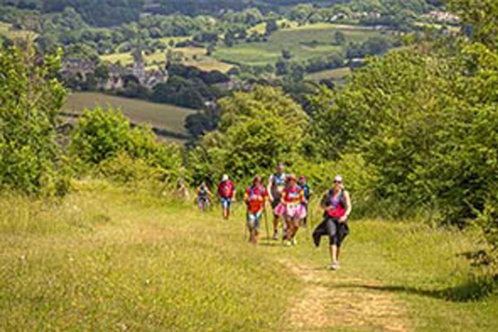 Trekkers walking up a steep hill in the Surrey countryside.